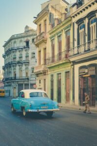 Classic blue car driving along a vibrant street in Old Havana, Cuba. Embodying the city's vintage charm.